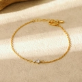 Détail du bracelet chaîne fine dorée avec deux zircons brillants et un fermoir mousqueton - Avril