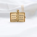 Golden book locket necklace with motivational engraving on white draped fabric background - Gold Book