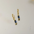 Details von eleganten goldenen Creolen mit rechteckigen dunkelblauen Edelsteinen - September
