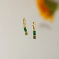 Elegant 18K gold starburst earrings with emerald-cut green gemstones on a beige base - May
