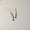 Detailansicht der goldenen Brisur-Ohrringe mit smaragdgeschliffenen blauen Edelsteinen - Dezember