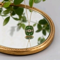 Detail von goldenem Evil-Eye-Anhänger mit grünem Emaille und Kristallen an einer Kette - Schutzauge - Grüne Ausführung