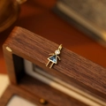 Golden girl pendant with round clear gem and triangular blue stone on a wood box - December Girl