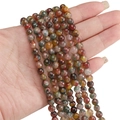 Faceted natural Indian agate beads in mixed colors held for scale on a white background - Vibrant Floral Mix