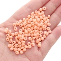 Nude pink 5mm glass seed beads in palm showing small round DIY jewelry components - Orange-pink Approx. 5x5mm Pore Size Approx. 1mm 10g/pack Approx. 100 Pieces