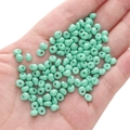 5mm mint green glass seed beads for DIY jewelry held in hand to show size and texture - Greenish-blue Approximately 5x5mm Pore Size Approximately 1mm 10g/pack Approximately 100 Pieces.