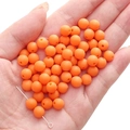 Matte bright orange acrylic round beads for DIY jewelry making held in a hand - Orange Red