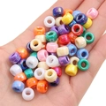 Colorful AB coated acrylic pony beads with pearlescent finish held in palm for scale - Diameter approx. 9mm, Height approx. 6mm, Hole approx. 3.5/4mm / AB Coated Solid Mixed Colors (Approx. 100 pcs/Pack)