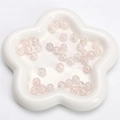 Pink cracked glass beads for DIY jewelry making displayed on a white petal tray - Pink