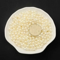 Detailed view of cream white ABS imitation pearls with a coin for size reference - 8mm 130 Pcs/Pack (With Hole) / Off White
