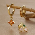 Macro detail of gold clover zircon earrings and cherry stud with gemstone inlays - Gold