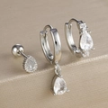 Macro view of three-piece silver drop zircon earring set on a beige textured stand - Silver-White Style