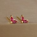 Close-up of gold flower earrings with marquise-cut ruby zircons on a metal surface - Marquise Double Zirconia Leaf Stud (Y20283) / Gold-Red