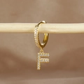 Macro detail of gold-plated earring with letter F pendant and micro-pave zircons - 1 Piece / Gold - Letter F