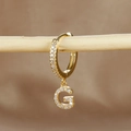 Macro detail of gold-plated hoop earring with G letter pendant and micro-pave zircons - 1 Piece / Gold - Letter G