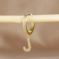 Detail of gold letter J huggie earring featuring pave-set zircon stones on wood stand - 1 Piece / Gold - Letter J
