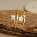 Close-up of gold flower stud earrings with white zircons on a natural wood base - Gold Four-petal Flower White Zircon Hoop Earrings (Y20309)