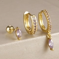 Gros plan de boucles d'oreilles dorées avec zircon violet sur fond métallique chic - Métal Doré Avec Zirconia Violet (Y26259)