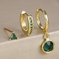 Detailed view of three gold-plated earrings set with emerald green zircon stones - Gold-Green