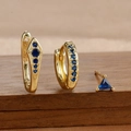 Detail-Makroaufnahme von S925 Sterlingsilber-Ohrringen mit blauen Zirkonia auf Satin - Dreiteiliges Set / Gold-Dunkelblau
