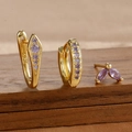 Makroaufnahme von S925 Silber-Ohrringen in Gold mit lila Zirkonia auf Holzgrund - Dreiteiliges Set / Gold-Lila