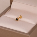 Gros plan d'une boucle d'oreille dorée avec cristal noir sur tissu de soie rose - Black Zirconia Ear Bone Stud / Or Noir