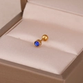 Gros plan sur un clou d'oreille doré avec pierre bleue sur un tissu en satin champagne - Or & Bleu Foncé