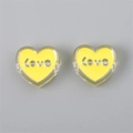 Close-up of yellow heart-shaped acrylic charms with silver Love inscription for DIY jewelry - Heart (LOVE) / 4 Pieces/Pack (24x22x9mm) / Yellow