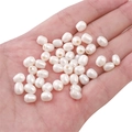 Macro detail of white oval freshwater pearl beads for DIY jewelry making in palm - Rice Bead (5-6mm) / White