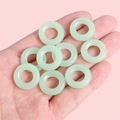 Handheld view of small pale green glass rings with a smooth polished jade-like finish - Diameter approx 16mm, Inner Diameter approx 8mm (5 Pieces/Pack) / Light Green