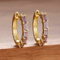 Détail de boucles d'oreilles dorées avec zircons violets rectangulaires sur bois - Violet Or