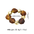 Detail view of elastic bracelet with amber resin beads and gold geometric metal accents - Amber