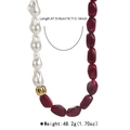 Détail de collier en perles baroques avec perles de résine rouges et boule dorée ondulée - Rouge