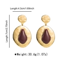 Detail view of large geometric gold earrings with dimensions 7cm height and 4.3cm width - Burgundy