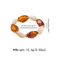 Vista de detalle de pulsera de cuentas de resina ámbar y blanca con piezas doradas - Ámbar