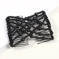 Dettaglio di un pettine magico con perle nere e denti in metallo flessibili su sfondo bianco - Nero