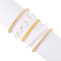 Detalle de un juego de cinco pulseras doradas con perlas blancas y dijes de flores - Estilo de Flor