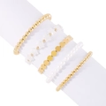 Detalle del juego de cinco pulseras de cuentas doradas y perlas en un soporte blanco - Estilo Estrella