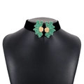 Detail of black velvet choker featuring symmetrical green enamel flowers and gold centers - Green