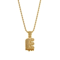 Macro shot of gold letter E pendant with white zircons and red lava drip detail - Letter E