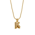 Close-up of golden letter K pendant with micro-pave zircons and orange lava drop detail - Letter K