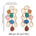 Detail shot of oversized bohemian earrings with colorful resin stones and gold metal trim - Colorful