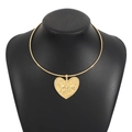 Close-up of golden collar necklace featuring an embossed heart pendant with tribal face pattern - Gold
