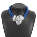 Detailed macro view of an oversized silver flower pendant on a dark blue beaded necklace - Blue Silver
