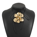 Detalle de un colgante de flor dorada con borde negro en un collar de cordón negro - Collar Oro Negro