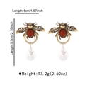 Detalle de pendientes de abeja dorados vintage con piedras rojas y perlas de lágrima - Pendientes de Gota de Abeja y Perla / Pendientes de oro