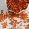 Polished bright orange glass bugle beads in a ceramic bowl for DIY craft jewelry - Size 3 Bugle 2x7mm / Orange Red