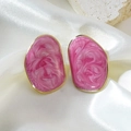 Boucles d'oreilles irrégulières en résine rose marbrée avec monture dorée sur du satin - Rose
