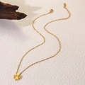 Close-up of golden four-leaf clover necklace with radial texture and fine link chain - Patterned Clover Style