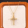 Macro detail of gold cross pendant with central zircon on rustic linen backdrop - Round Bead Spliced Rhinestone Cross Necklace (MY540)